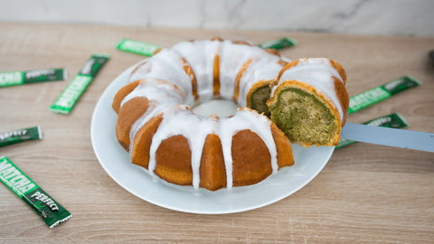 Matcha Cake drizzled with icing surrounded by perfect ted matcha sachets.