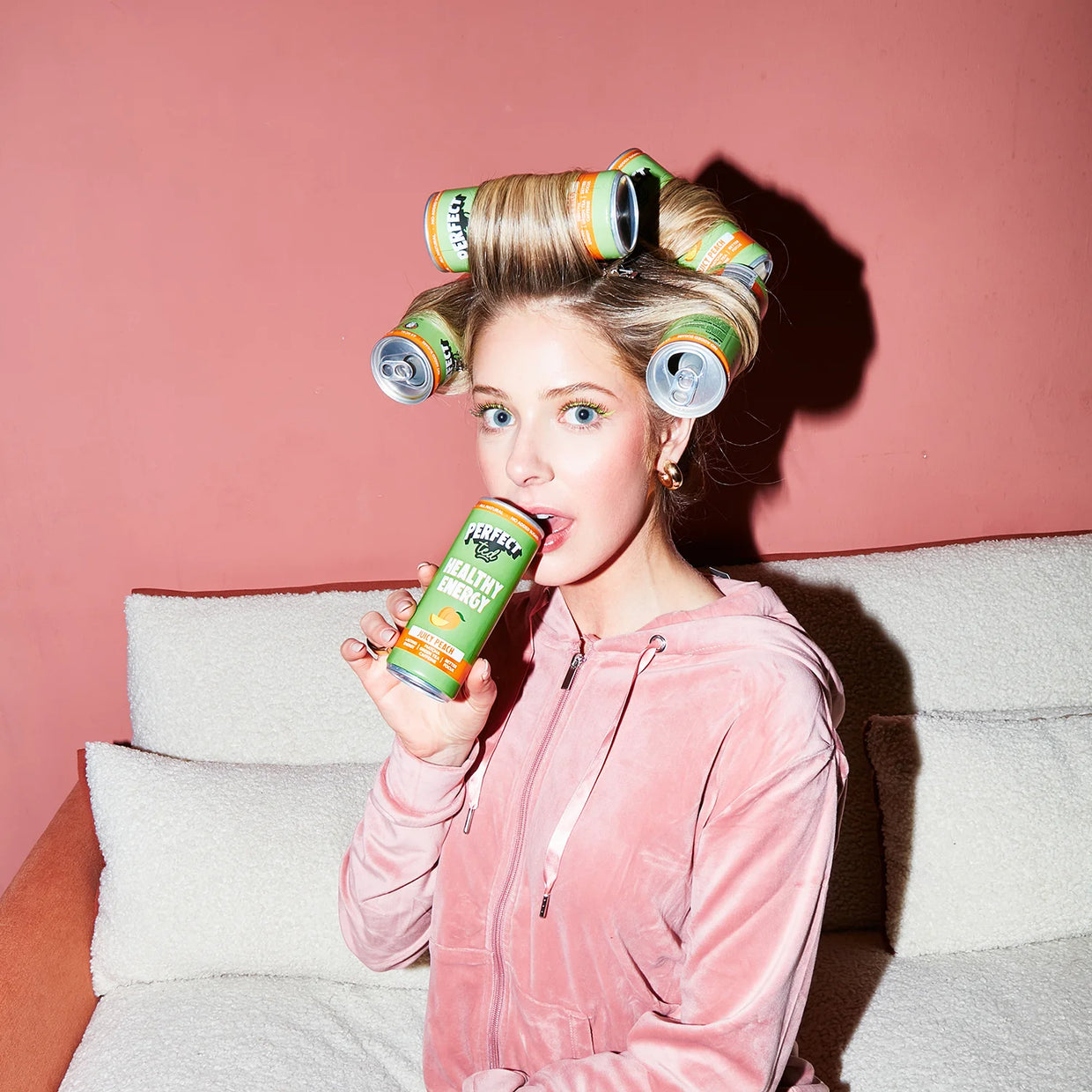 Marisa drinking juicy peach in a light pink tracksuit and peach can hair rollers